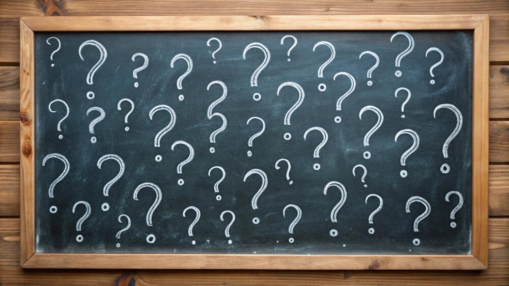 Blackboard full of question marks symbolizing unanswered questions about parents’ childhood trauma and family history