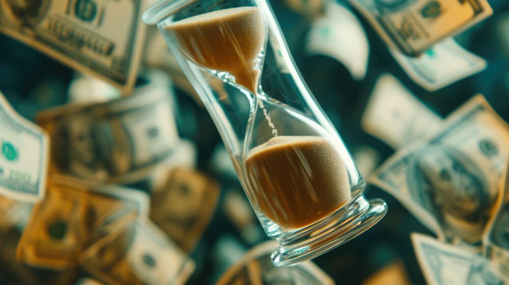 Hourglass surrounded by money — time running out on financial obligations while mourning.